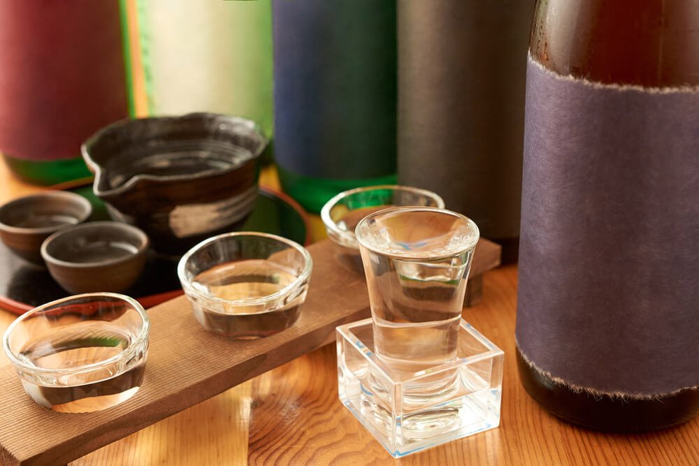 10.さまざまな日本酒の瓶に囲まれるお猪口とグラス.jpg